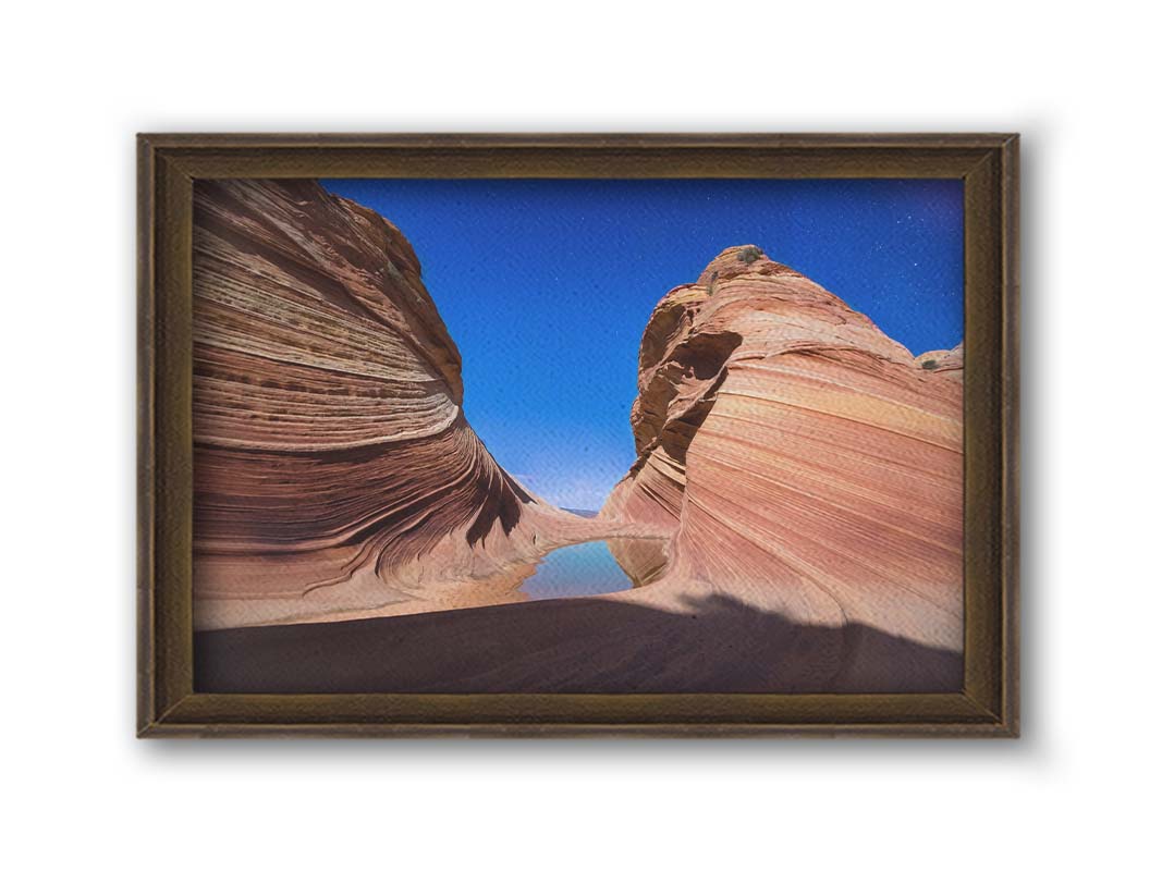 Photo of the "Wave" rock formation at Coyote Buttes North in Utah. A bright night shot captures stripes of sandstone layers forming orange waves against a starry blue sky. Printed on canvas and framed.