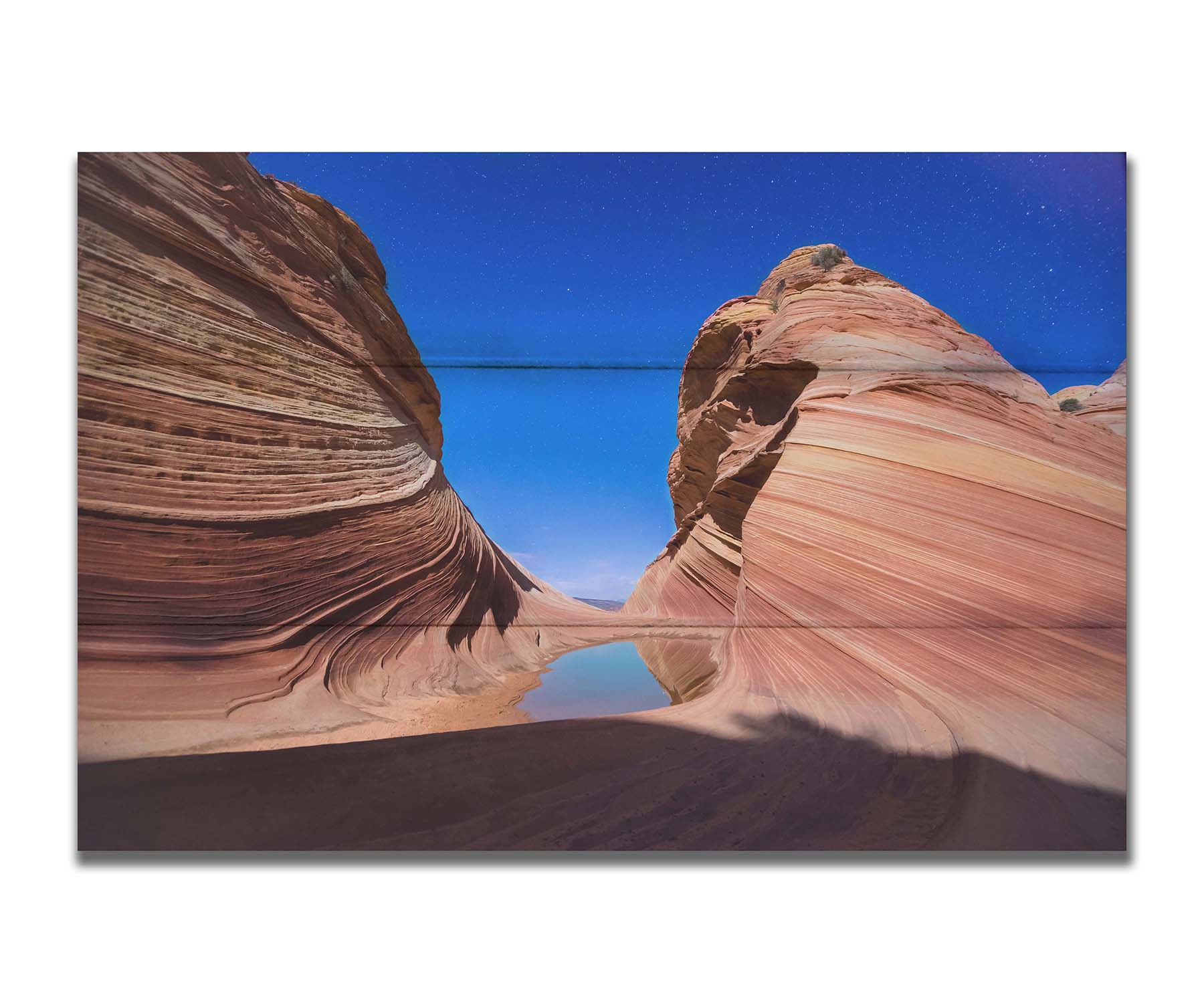 Photo of the "Wave" rock formation at Coyote Buttes North in Utah. A bright night shot captures stripes of sandstone layers forming orange waves against a starry blue sky. Printed on a box board.