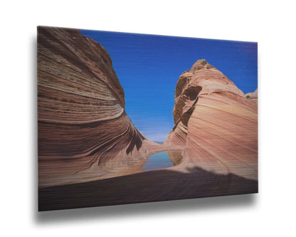 Photo of the "Wave" rock formation at Coyote Buttes North in Utah. A bright night shot captures stripes of sandstone layers forming orange waves against a starry blue sky. Printed on metal.