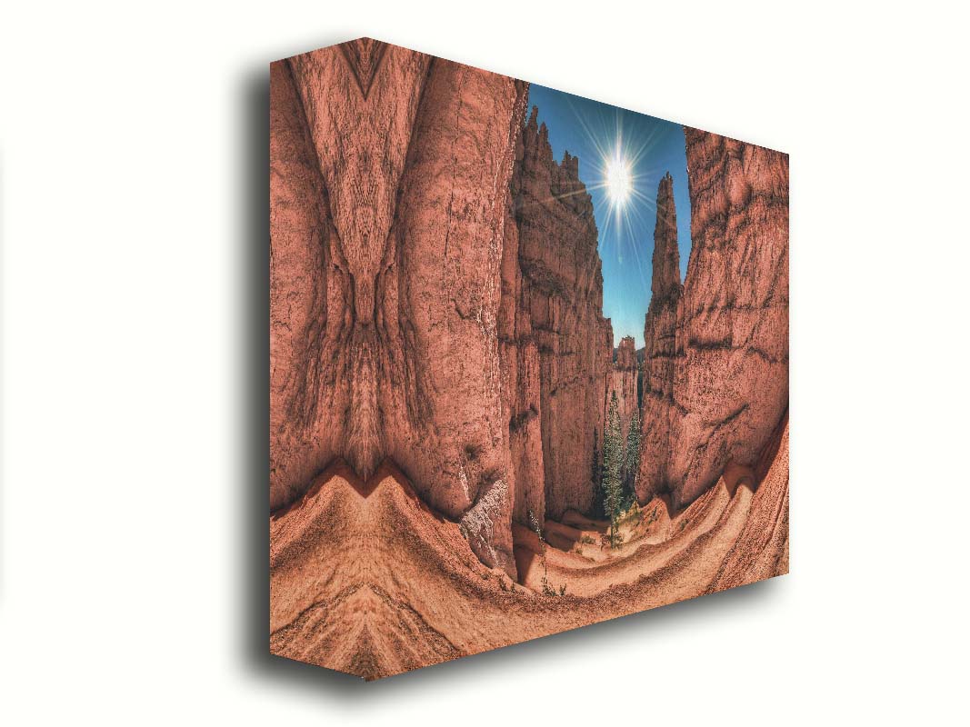 Photo of the Navajo Loop Switchbacks rock formation at Bryce Canyon National Park in Utah. It is taken wit a fish eye lens perspective which emphasizes the height and depth of the structures. A bright blue sky peeks out between parallel walls of red stone, and the bright white rays of the perfectly centered sun shine down between. Printed on canvas.