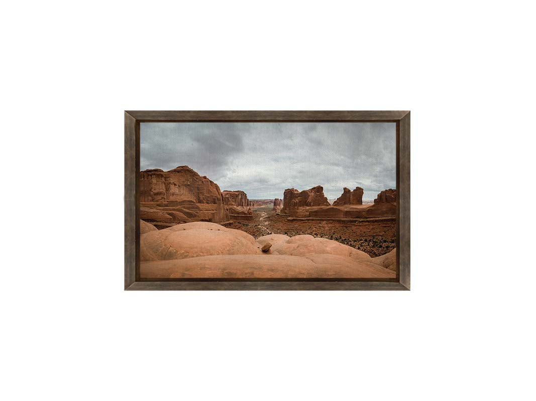 A photograph of Park Avenue at Arches National Park, looking out between rocky plateaus. Printed on canvas and framed.