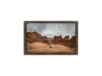 A photograph of Park Avenue at Arches National Park, looking out between rocky plateaus. Printed on canvas and framed.