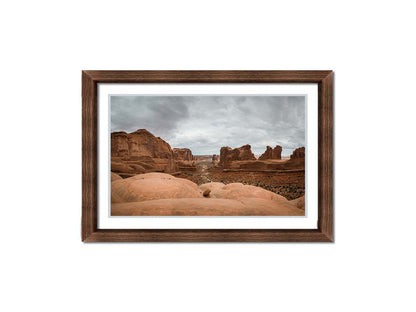 A photograph of Park Avenue at Arches National Park, looking out between rocky plateaus. Printed on paper, matted, and framed.