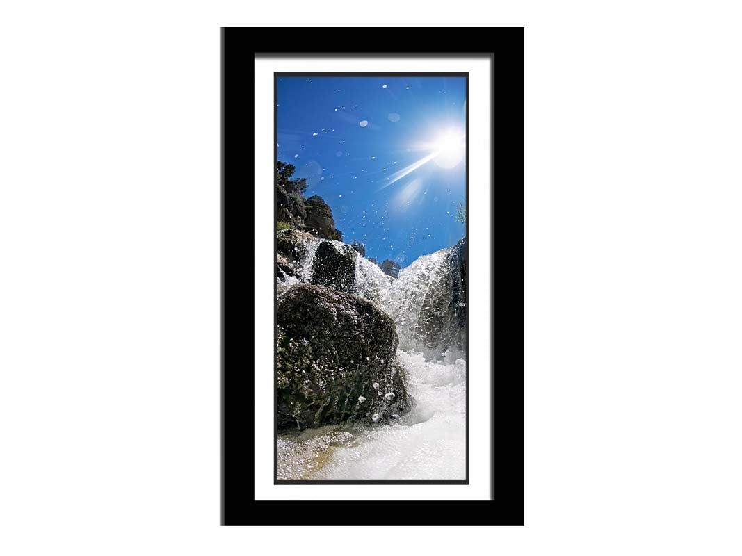 A photo looking up at the waterfalls filling the mountain hotsprings in Utah. The sky is clear and vibrant blue. Printed on paper, matted, and framed.