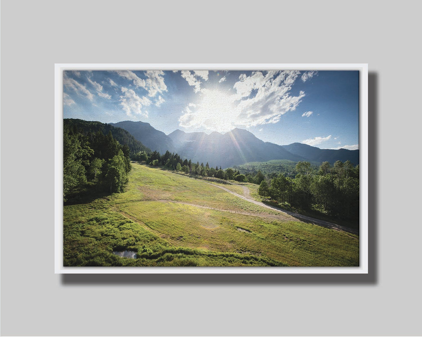 A photo of the sun shining brightly over Mount Timpanogos. The hillsides and forest are the fresh green of springtime. Printed on canvas in a float frame.