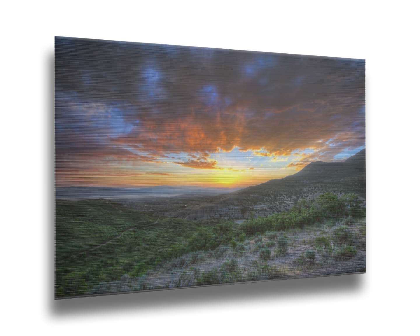 A photo of the sunset at Piestewa Peak in Provo Canyon, Utah. The gold light from the sun reflects off gray clouds about the green foliage surrounding the mountain. Printed on metal.