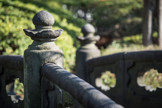 A photo of a detailed stone bridge, with a background of green plantlife.