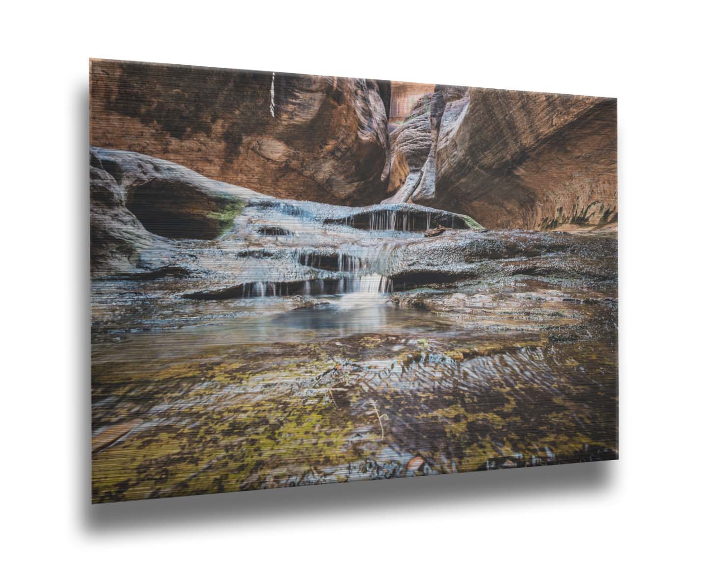 A photo of the Left Fork North Creek flowing through the Subway slot canyon in Utah's Zion National Park. It flows toward the camera, tumbling over slabs in the sandstone to create small waterfalls. Printed on metal.