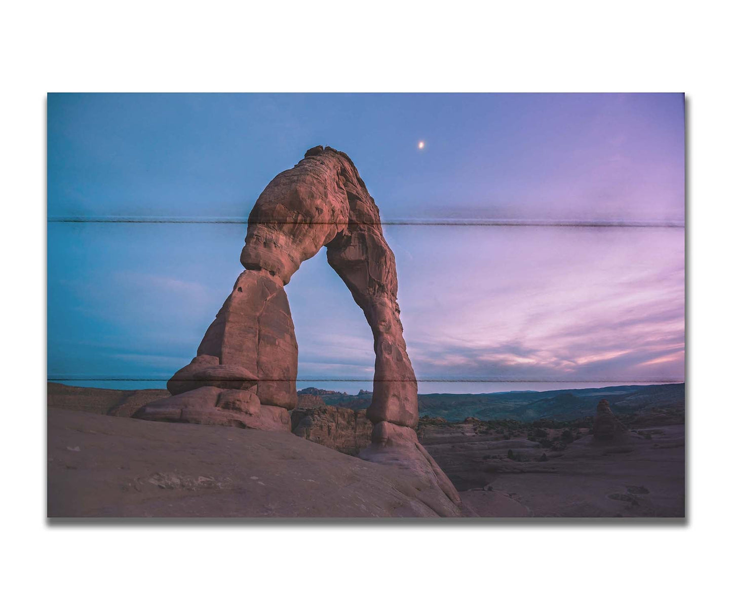 A photo of the Delicate Arch rock formation in Arches National Park, Utah. The blues and purples of the sky at sunset compliment the oranges and browns of the sandstone arch. Printed on a box board.