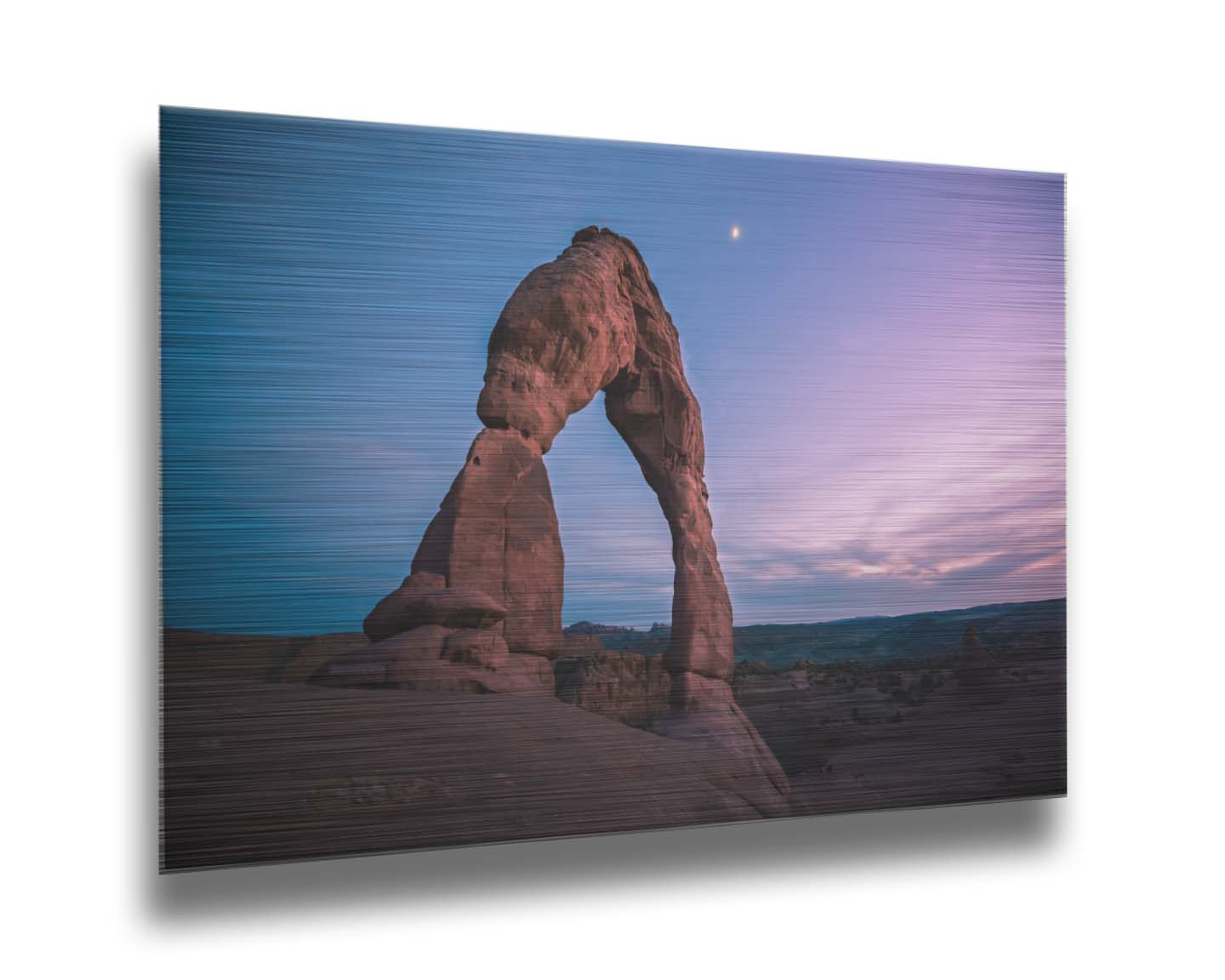 A photo of the Delicate Arch rock formation in Arches National Park, Utah. The blues and purples of the sky at sunset compliment the oranges and browns of the sandstone arch. Printed on metal.