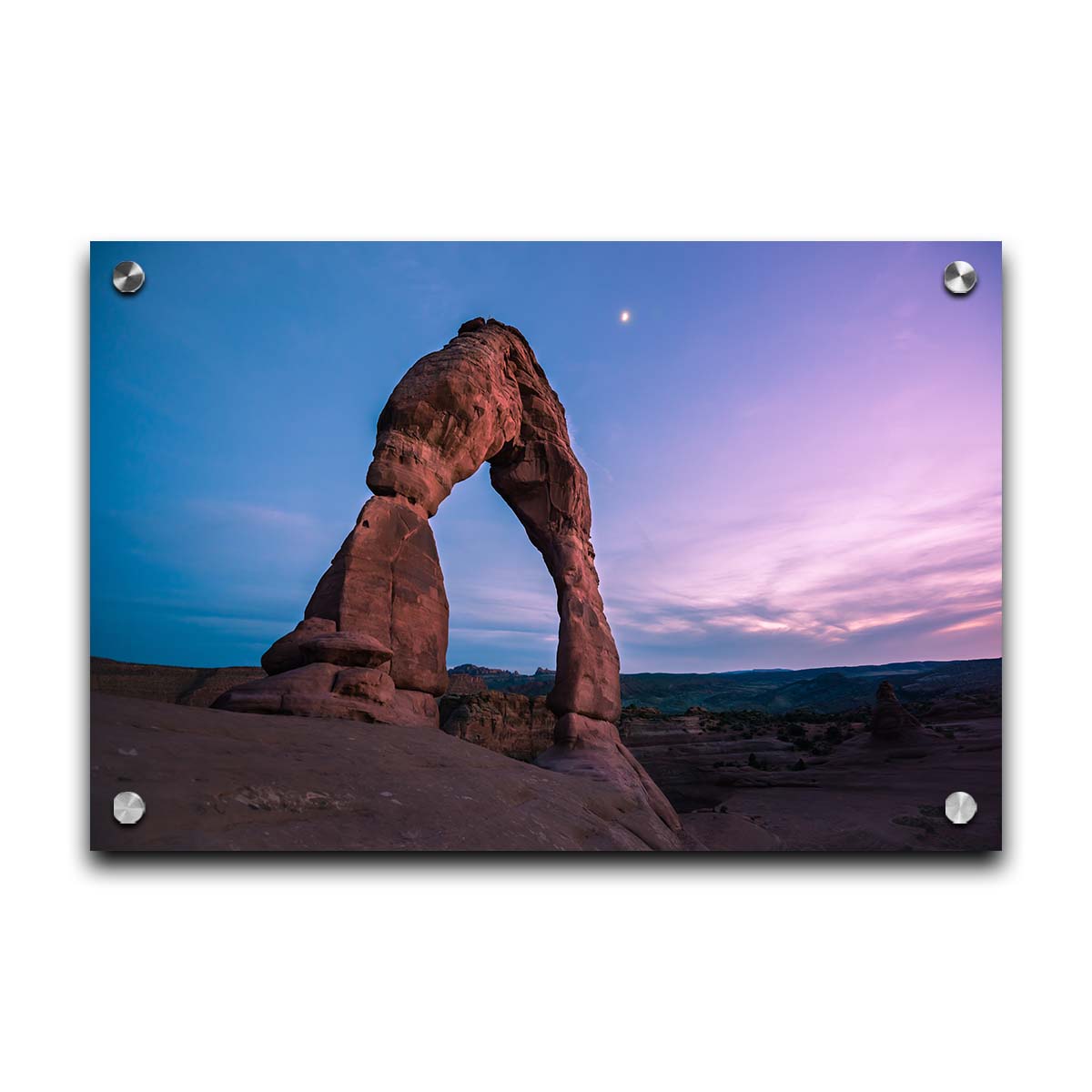 A photo of the Delicate Arch rock formation in Arches National Park, Utah. The blues and purples of the sky at sunset compliment the oranges and browns of the sandstone arch. Printed on acrylic.