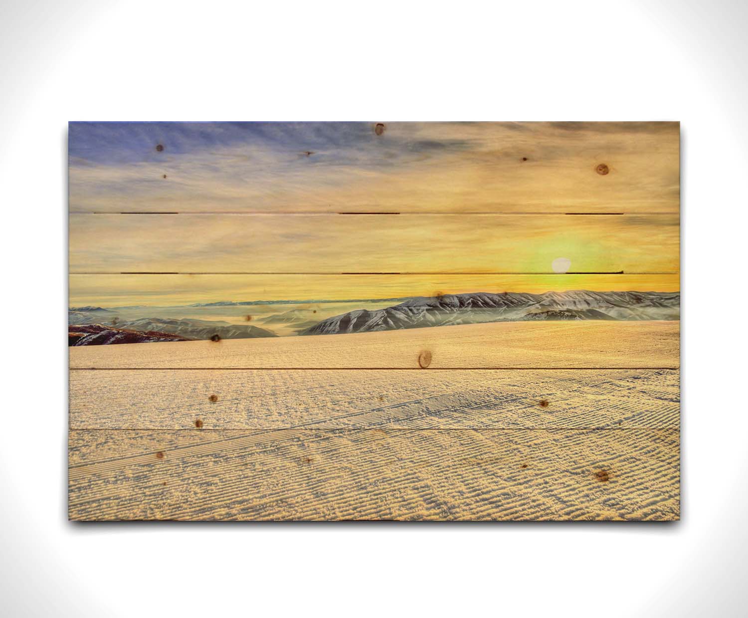 A photo of the sunrise over Sundance Ski Resort. The sun creates a yellow reflective glow on the freshly groomed ski slope. Printed on a wood pallet.