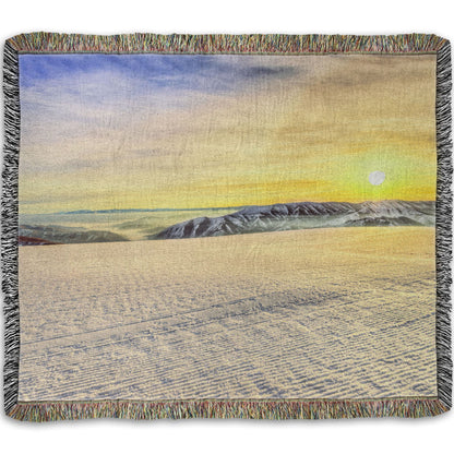 A woven throw blanket designed with a photo of the sunrise over a freshly groomed ski slope at Sundance Ski Resort.