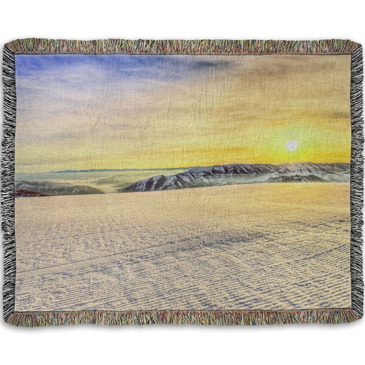 A woven throw blanket designed with a photo of the sunrise over a freshly groomed ski slope at Sundance Ski Resort.