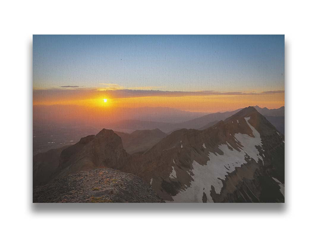 A photo of the sunset from the top of Mount Timpanogos in Utah. Snow highlights the edges of the mountain ridges. Printed on canvas.