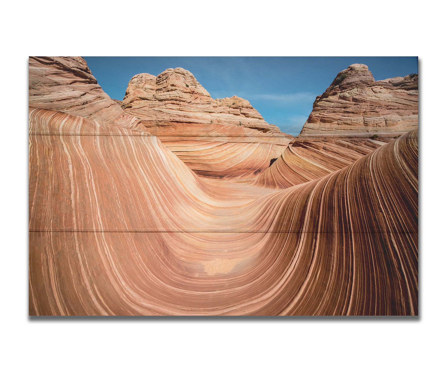 A photo of the "Wave" rock formation at Coyote Buttes North in Utah. The wavy sandstone layers create rolling waves where they have been carved out of the mountainside. The orange hues of the stone are sharply contrasted by the vibrant blue of the sky. Printed on a box board.