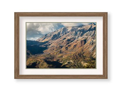 A photo of Mount Timpanogos during the fall. Taken from Piestewa Peak, this photo looks down across groves of trees turning color, appearing small from the altitude. Printed on paper, matted, and framed.