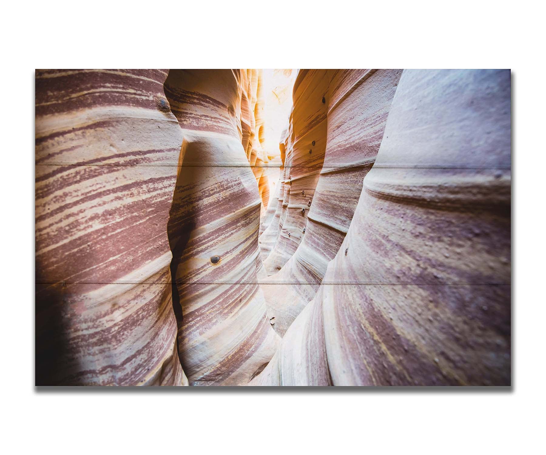 A photo of Zebra Slot Canyon in Escalante National Monument, Utah. A tight formation of alternating, red and white striped stone walls wave into the distance, where yellow light can be seen. Printed on a box board.