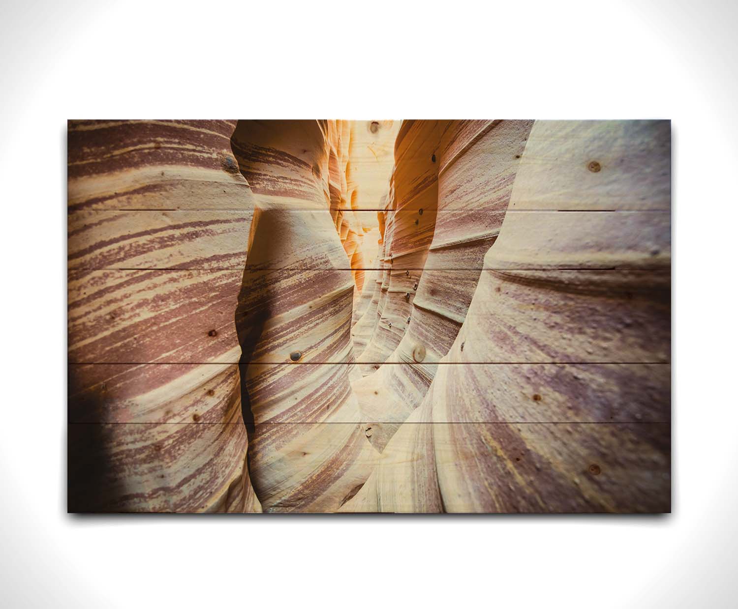 A photo of Zebra Slot Canyon in Escalante National Monument, Utah. A tight formation of alternating, red and white striped stone walls wave into the distance, where yellow light can be seen. Printed on a wood pallet.