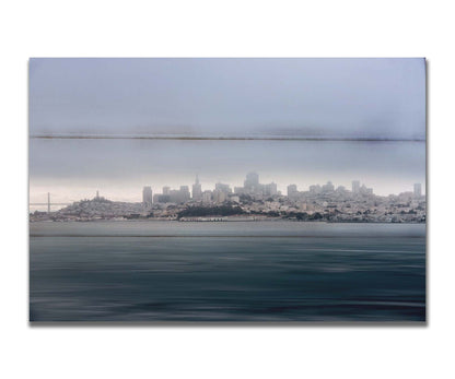 A photo of San Francisco bay taken from Vista Point. The long exposure of the photo creates a smoothing effect on the dark waters, and a heavy cloud of fog site just across the top of the city on the horizon. Printed on a box board.