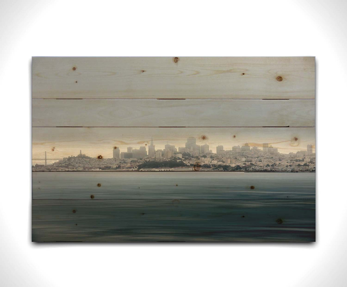 A photo of San Francisco bay taken from Vista Point. The long exposure of the photo creates a smoothing effect on the dark waters, and a heavy cloud of fog site just across the top of the city on the horizon. Printed on a wood pallet.