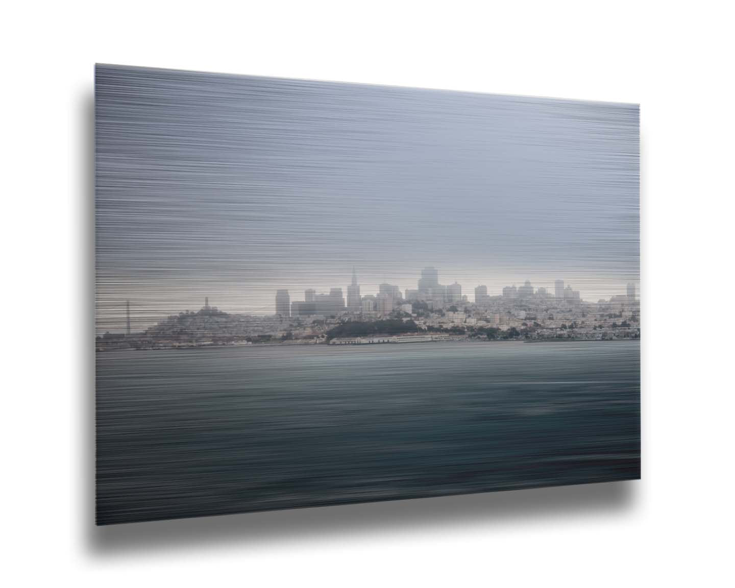 A photo of San Francisco bay taken from Vista Point. The long exposure of the photo creates a smoothing effect on the dark waters, and a heavy cloud of fog site just across the top of the city on the horizon. Printed on metal.