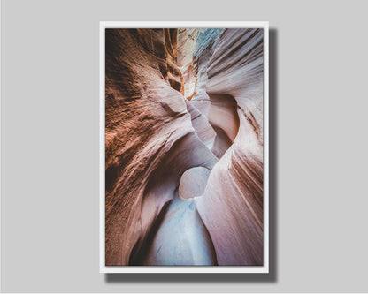 A photo looking through Peek-A-Boo slot canyon near Escalante, Utah. The wavy layers of sandstone have an unusual, surreal appearance. Printed on canvas in a float frame.