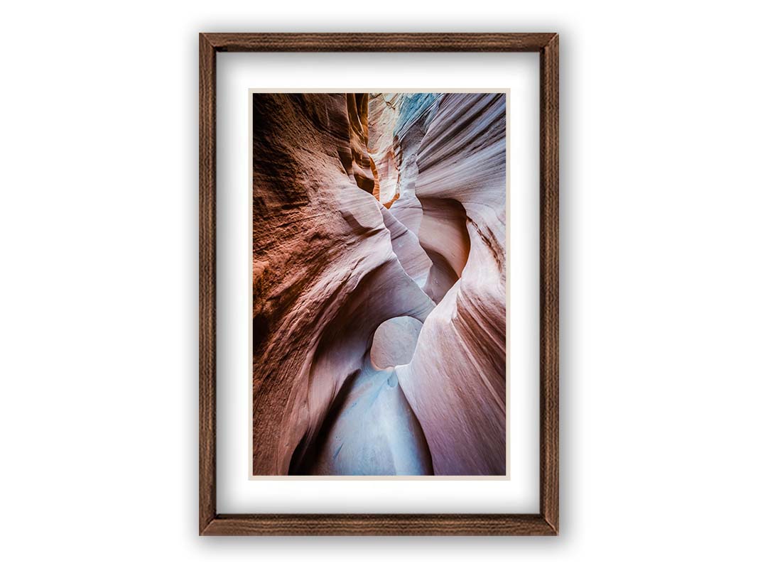 A photo looking through Peek-A-Boo slot canyon near Escalante, Utah. The wavy layers of sandstone have an unusual, surreal appearance. Printed on paper, matted, and framed.