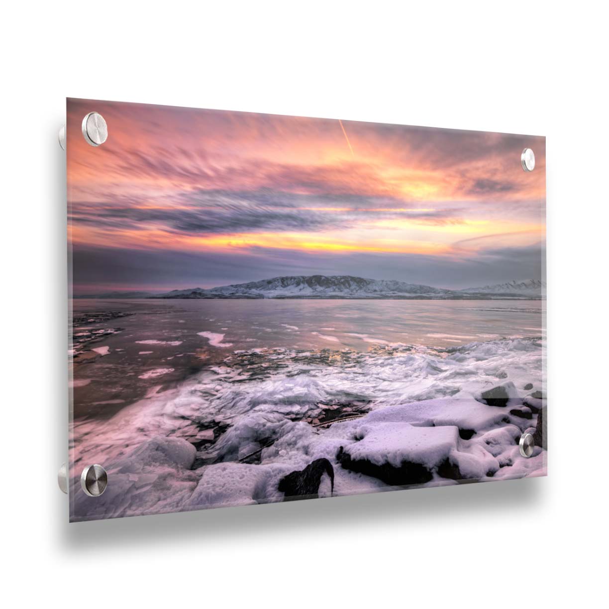 A photo of the sun setting at Mount Timpanogos, Utah, one Christmas evening. Its golden light can be seen peeking through the clouds across the horizon of a frozen lake, wind pushing thin sheets of ice up onto the shore. Printed on acrylic.