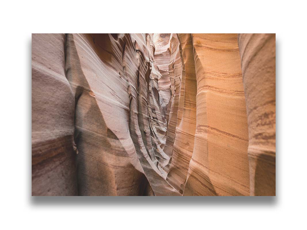 A photo of the Zebra Slot Canyon at Grand Staircase-Escalante National Monument, Utah. The red and orange sandstone stripes alternate in sharp waves down the length of the narrow passageway. Printed on canvas.