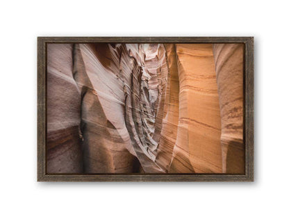 A photo of the Zebra Slot Canyon at Grand Staircase-Escalante National Monument, Utah. The red and orange sandstone stripes alternate in sharp waves down the length of the narrow passageway. Printed on canvas and framed.