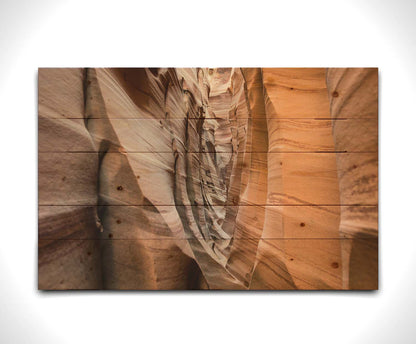 A photo of the Zebra Slot Canyon at Grand Staircase-Escalante National Monument, Utah. The red and orange sandstone stripes alternate in sharp waves down the length of the narrow passageway. Printed on a wood pallet.