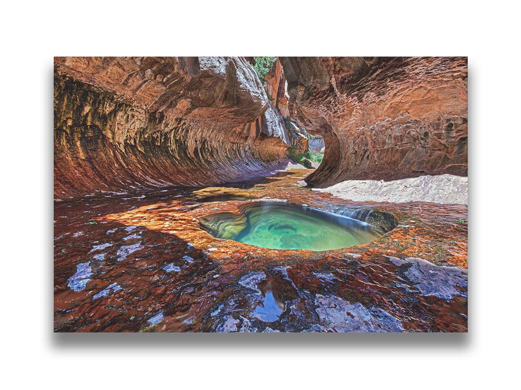 A photo showcasing a pool inside The Subway, or the Left Fork of North Creekâ€” a slot canyon in Zion National Park, Utah. The red rock walls and ground contrast with a bluegreen pool of water. Printed on canvas.