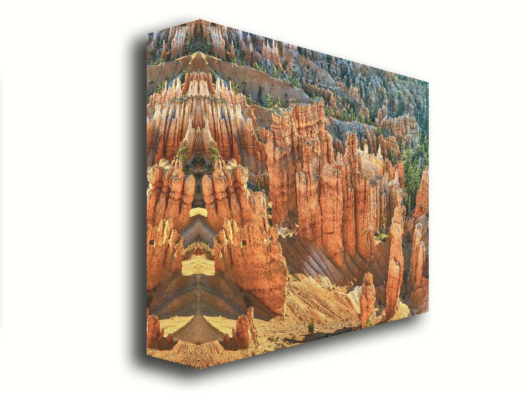 A photo of towering sandstone pillars along the Navajo Loop trail at Bryce Canyon National Park in Utah. The orange and yellow stone is contrasted by bursts of evergreens scattered throughout the walls of stone. Printed on canvas.