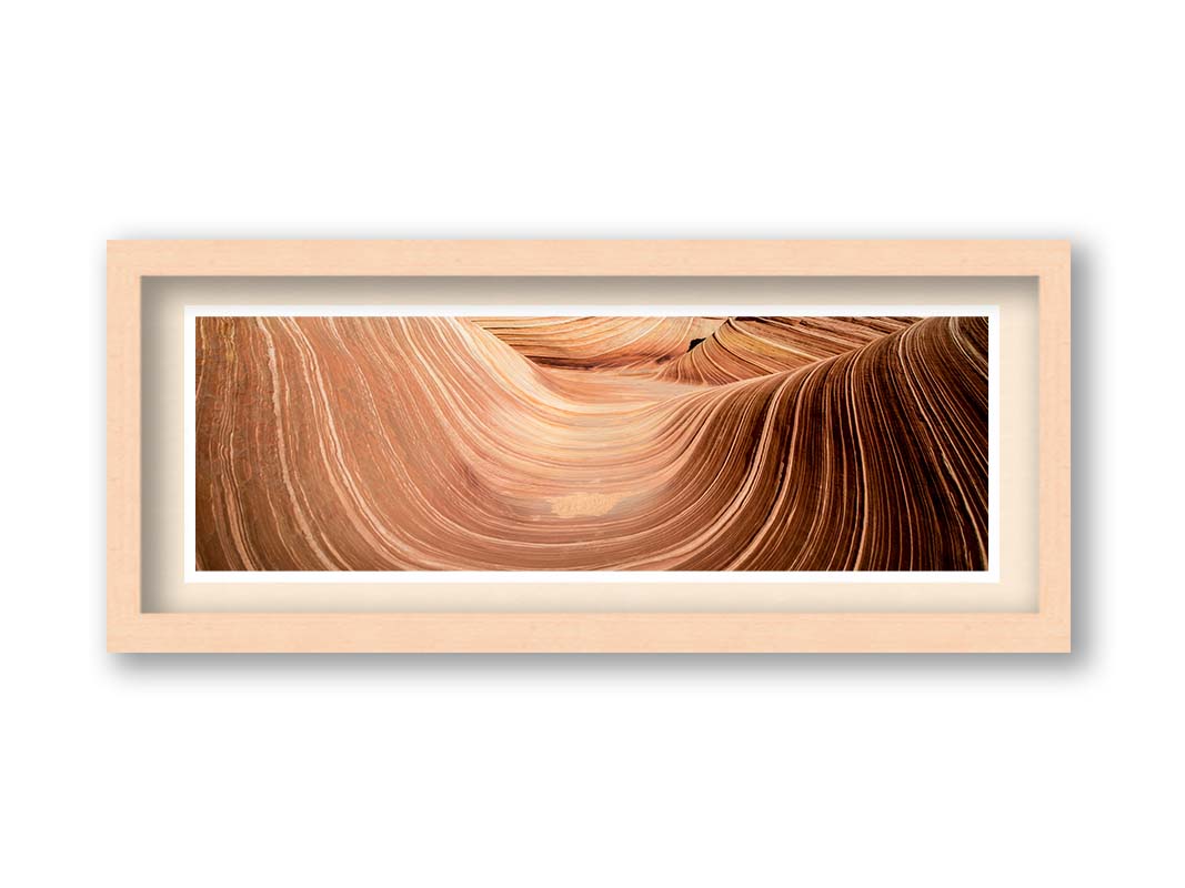 A panoramic photo of the Wave rock formation, at the Coyote Buttes North area of the Utah-Arizona border. The stripes of reddish-brown stone create a unique wave-like shape. Printed on paper, matted, and framed.