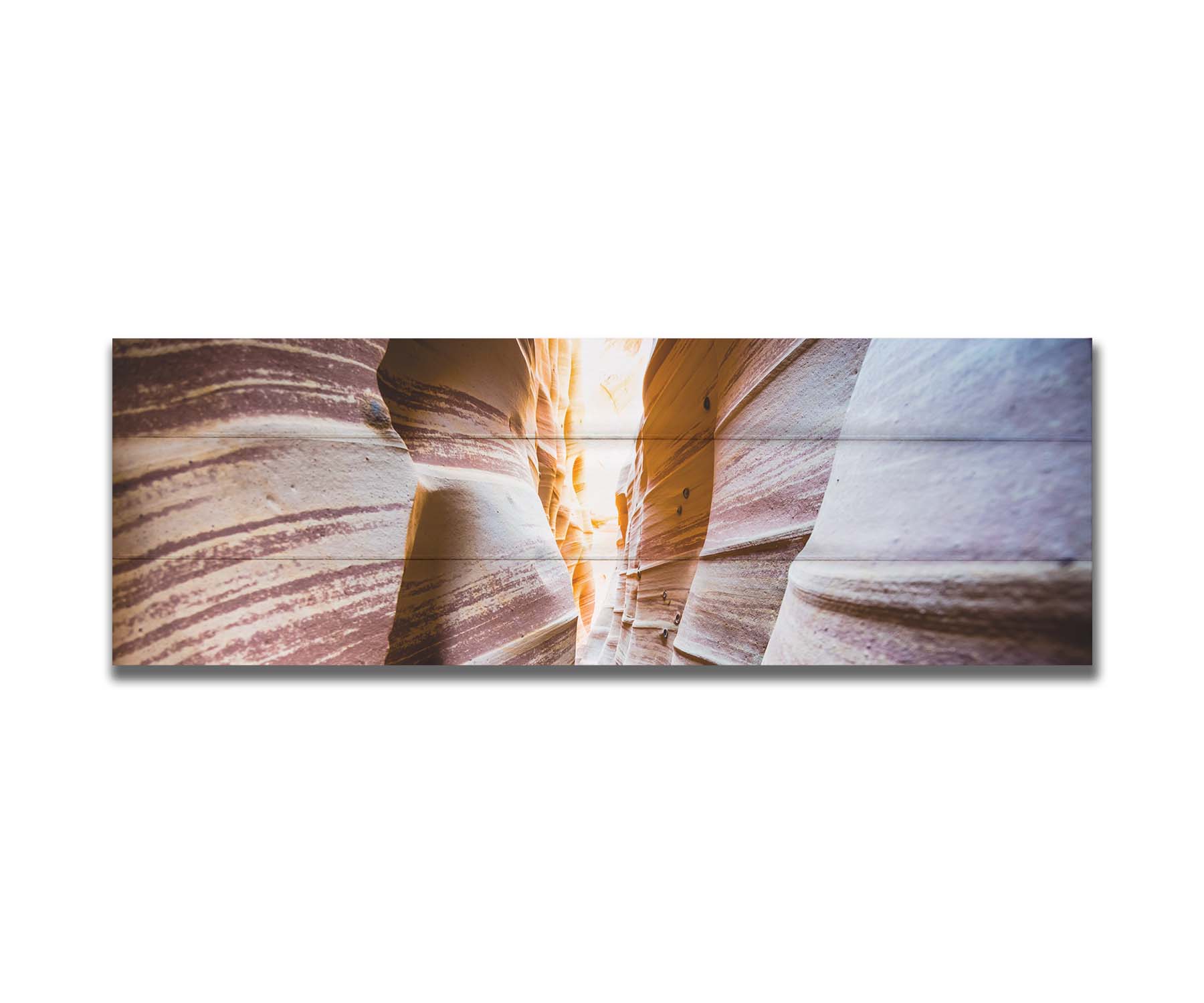 A photo looking down a narrow slot canyon. The walls of sandstone lead out into the light, creating added perspective with their red and white striped layers of stone drawing into the distance. Printed on a box board.