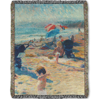 A woven throw blanket designed with a painting of a busy beach during the summer. People sit under umbrellas all along the sand, and in the foreground, two small children play.