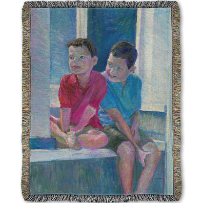 A woven throw blanket designed with a painting of two children sitting on a window ledge.