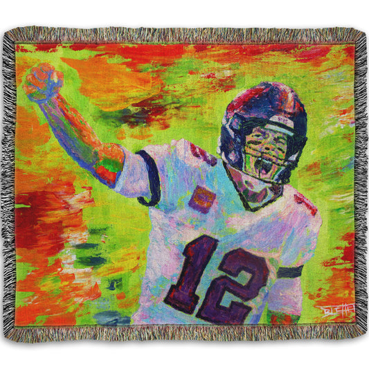 A woven throw pillow designed with a painting of American football player Tom Brady yelling with his fist in the air, rallying his teammates. Arbitrary colors and visible brushstrokes add to the energy of this painting, alongside the bright greens, reds, and oranges of the backdrop.