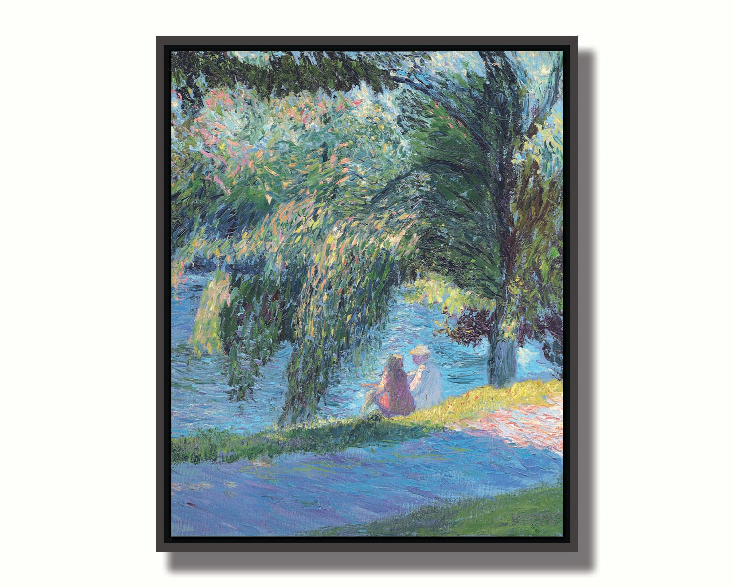 A painting of two people sitting by the water, near a park sidewalk, with a lare tree above them. Printed on canvas in a float frame.