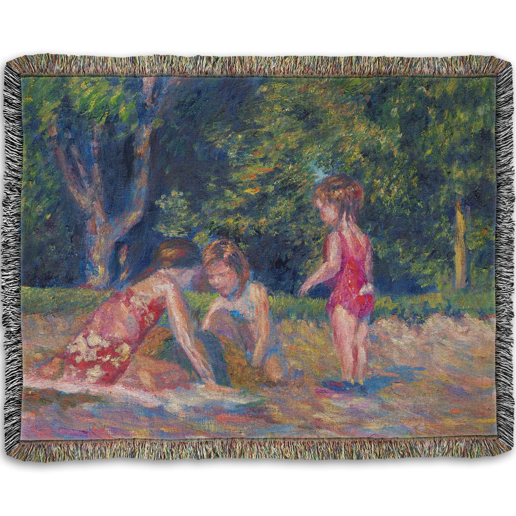 A woven blanket designed with a painting of three children playing in the sand at a beach. Their red swimsuits contrast the green foliage in the background.