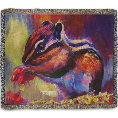Woven throw blanket designed with a painting of a chipmunk eating red berries, in a red and purple color palette using visible brush strokes. 