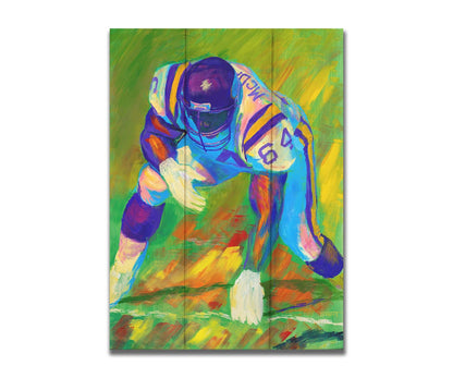 A painting of a football player, wearing white and purple, crouched on a bright green field. Printed on a box board.