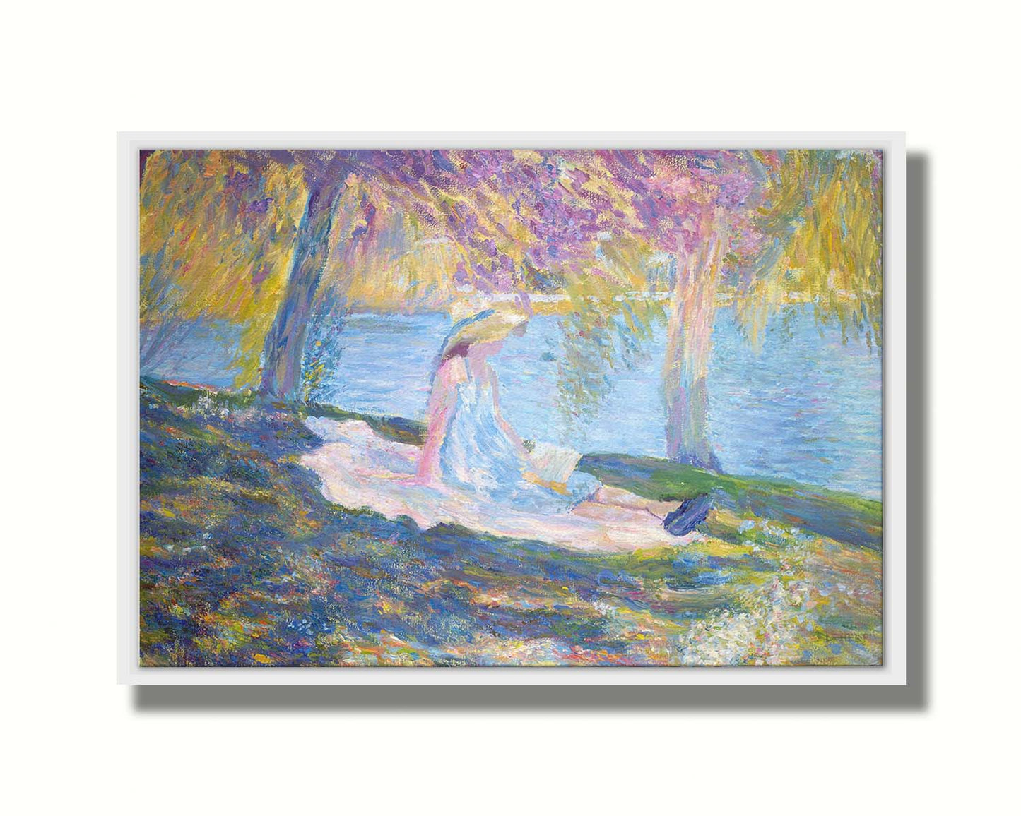 A painting of a person in a dress and sunhat, sitting on a blanket in the shade of trees by a lake, reading a book. Printed on canvas in a float frame.