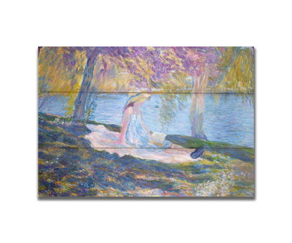 A painting of a person in a dress and sunhat, sitting on a blanket in the shade of trees by a lake, reading a book. Printed on a box board.