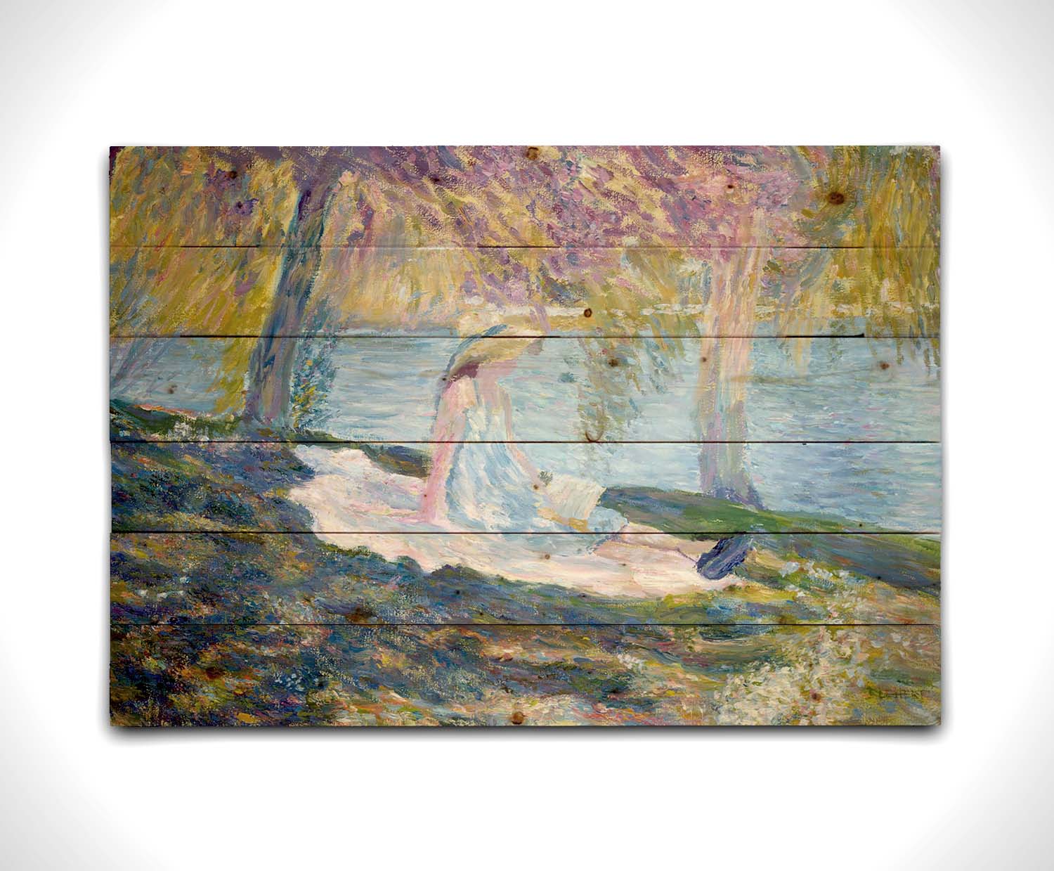 A painting of a person in a dress and sunhat, sitting on a blanket in the shade of trees by a lake, reading a book. Printed on a wood pallet.