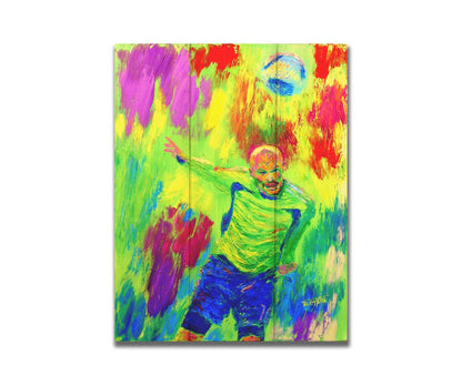 A painting of a soccer player running at a ball soaring toward them. It is painted in a bright, "neon" color palette with greens, reds, and blues. Printed on a box board.