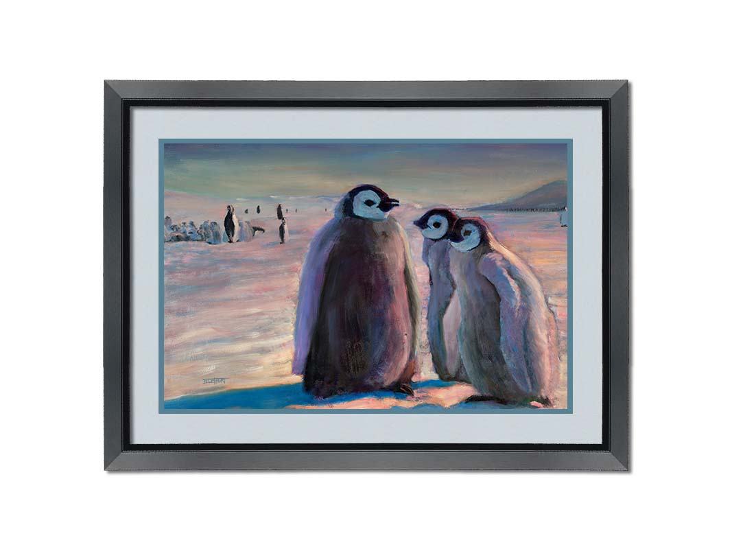 A painting of three young penguins, their colony in the background standing on the icy landscape. Printed on paper, matted, and framed.