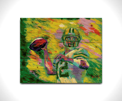 A painting of Green Bay Packers football player Aaron Rodgers, painted in the iconic yellow and green of the team and primed to throw a football. Printed on a wood pallet.