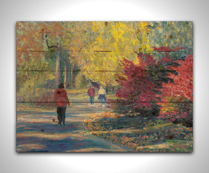 A painting of people walking in a park, the leaves changing to yellows and reds for autumn. Printed on a wood pallet.